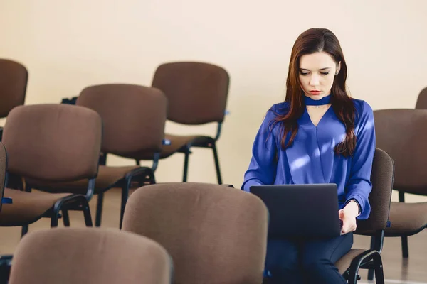 girl in auditorium works with laptop