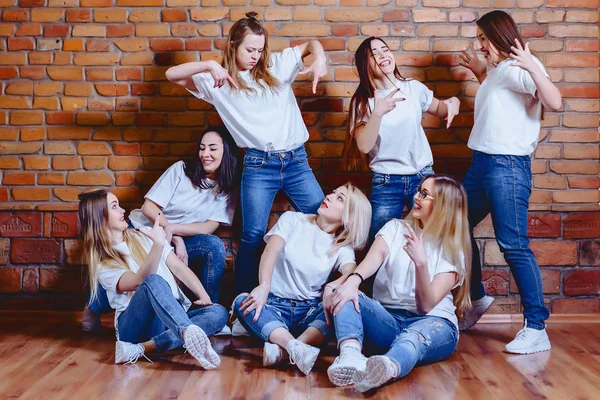 Niñas en jeans en el fondo de la pared de ladrillo —  Fotos de Stock