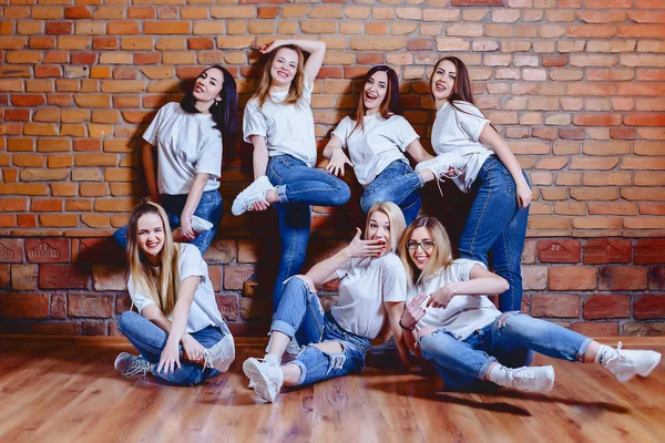 Niñas en jeans en el fondo de la pared de ladrillo —  Fotos de Stock