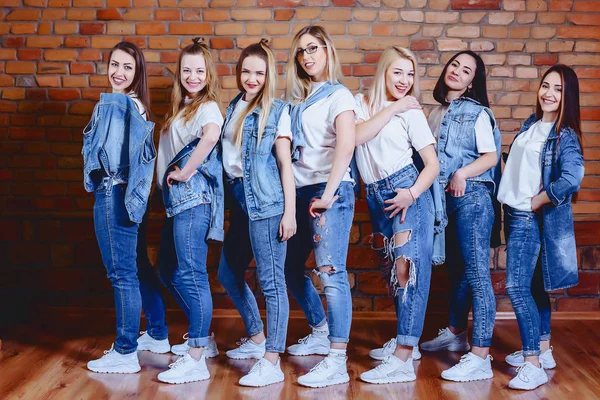 Niñas en jeans en el fondo de la pared de ladrillo —  Fotos de Stock