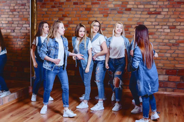 Meninas em jeans no fundo da parede de tijolo — Fotografia de Stock