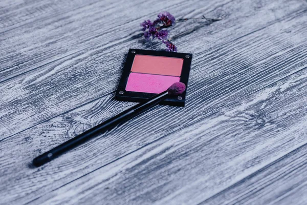 makeup brush on blush at wooden background