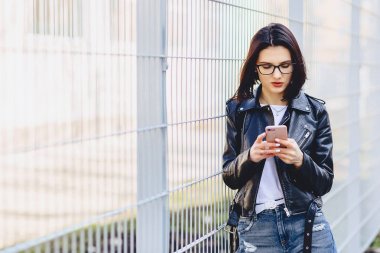 Kadın deri ceketli Street telefonunda mesajlaşma