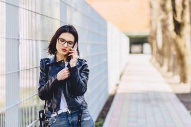 Kadın gülümser ve telefon konuşma bardaklarda deri ceketli