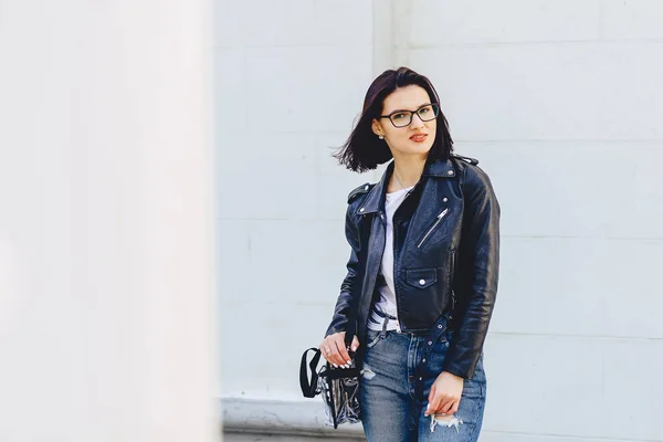 Woman in glasses in leather jacket on street