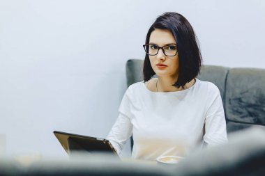 Kız kafede kahve içer ve tablet üzerinde çalışır