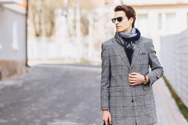 Stylish boy in sunglasses in coat with briefcase on street