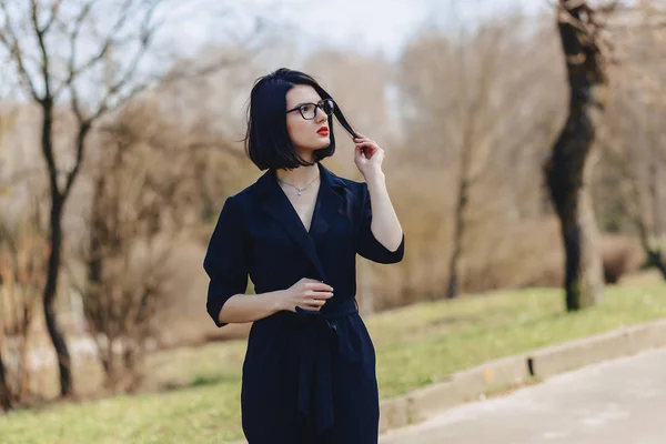 Mooi meisje in zwart pak onder struiken — Stockfoto