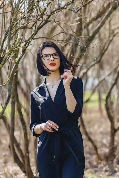 Menina bonita em terno preto entre arbustos — Fotografia de Stock