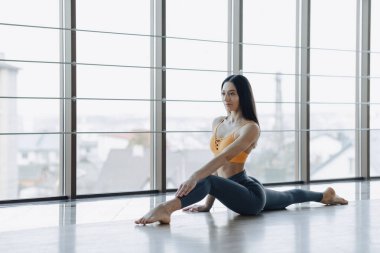 panoramik pencerelerin arka planına karşı katta Yoga ile Fitness egzersizleri yapan genç çekici kız