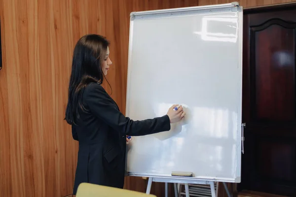 Mladá emotivní dívka v šatech obchodního stylu práce s flipchart v moderní kanceláři nebo posluchačům — Stock fotografie