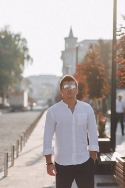 Güneşli bir günde Avrupa 'da bir sokakta yürürken tişörtlü şık bir genç.