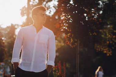 Güneşli bir günde Avrupa 'da bir sokakta yürürken tişörtlü şık bir genç.