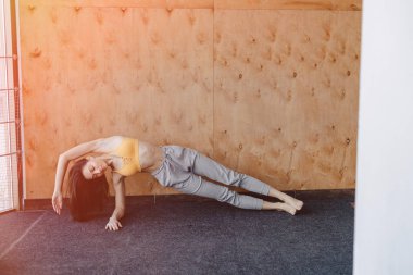 Ahşap bir arka planda yerde Yoga ile Fitness egzersizleri yapan genç çekici kız