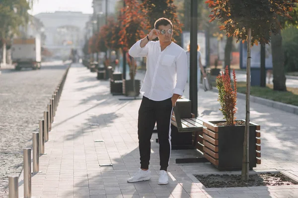 Ung snygg kille i skjorta går ner en europeisk gata på en solig dag — Stockfoto