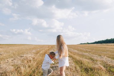 Sarışın küçük çocuk samanlı, beyaz saçlı annesiyle oynuyor. Yaz, güneşli hava, çiftçilik. Mutlu çocukluk. aile.