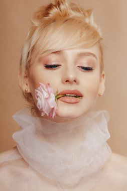 Sarışın, çekici bir kız. Moda çekimi, gül, basit bir geçmiş, stüdyo.