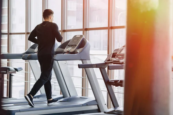 Spor salonundaki şık adam koşu bandında antrenman yapıyor. Sağlıklı yaşam tarzı. İyilik.
