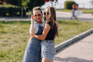 Parkta ya da sokakta yürüyen iki güzel kız. Güneşli bir yaz günü, neşe ve dostluklar.