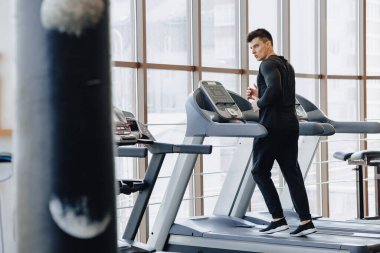 Spor salonundaki şık adam koşu bandında antrenman yapıyor. Sağlıklı yaşam tarzı. İyilik.