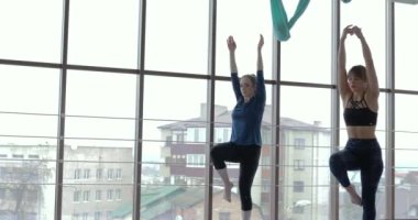 Kızlar büyük, aydınlık bir odada yoga çalışırlar. Koç ve öğrenci. spor eğitimi konsepti.