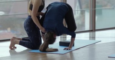 Kızlar büyük, aydınlık bir odada yoga çalışırlar. Koç ve öğrenci. spor eğitimi konsepti.