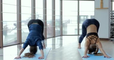 Kızlar büyük, aydınlık bir odada yoga çalışırlar. Koç ve öğrenci. spor eğitimi konsepti.