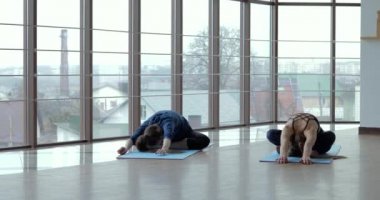 Kızlar büyük, aydınlık bir odada yoga çalışırlar. Koç ve öğrenci. spor eğitimi konsepti.