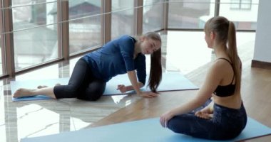 Kızlar büyük, aydınlık bir odada yoga çalışırlar. Koç ve öğrenci. spor eğitimi konsepti.