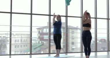 Kızlar büyük, aydınlık bir odada yoga çalışırlar. Koç ve öğrenci. spor eğitimi konsepti.