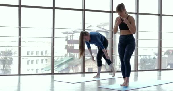 Girls practice yoga in a large, light room. coach and student. sport training concept. — Stock Video