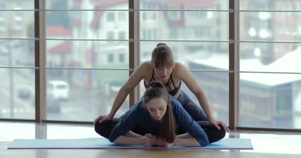 Niñas practican yoga en una habitación grande y luminosa. entrenador y estudiante. concepto de entrenamiento deportivo . — Vídeos de Stock