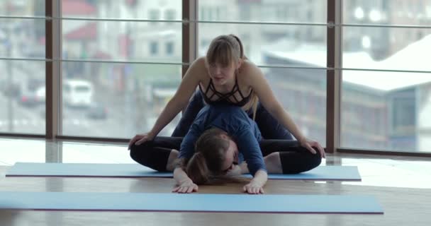 Niñas practican yoga en una habitación grande y luminosa. entrenador y estudiante. concepto de entrenamiento deportivo . — Vídeos de Stock