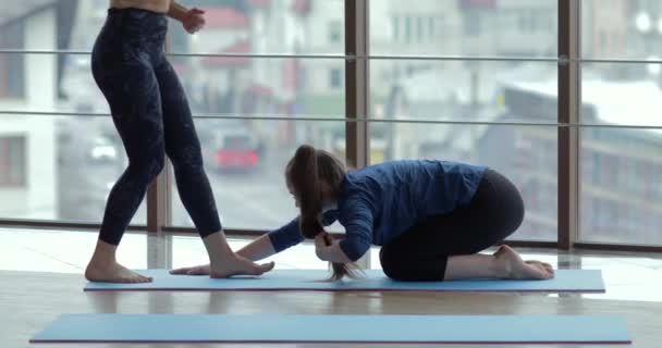 Niñas practican yoga en una habitación grande y luminosa. entrenador y estudiante. concepto de entrenamiento deportivo . — Vídeo de stock