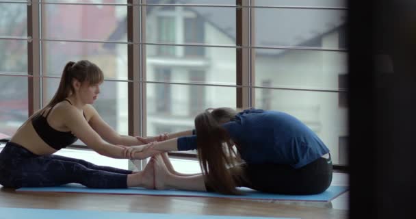 Le ragazze praticano yoga in una grande stanza luminosa. allenatore e studente. concetto di allenamento sportivo . — Video Stock