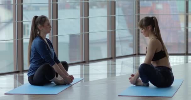 Kızlar büyük, aydınlık bir odada yoga çalışırlar. Koç ve öğrenci. spor eğitimi konsepti. — Stok video