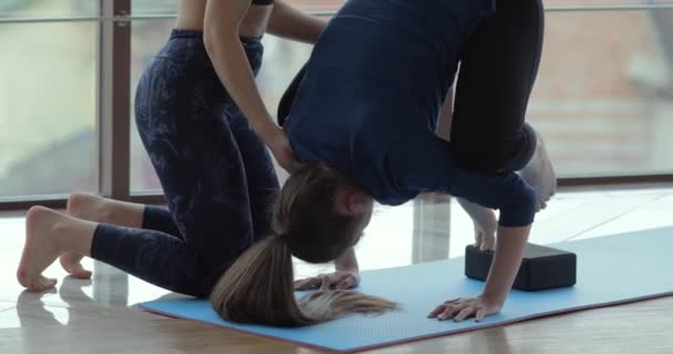 Kızlar büyük, aydınlık bir odada yoga çalışırlar. Koç ve öğrenci. spor eğitimi konsepti. — Stok video