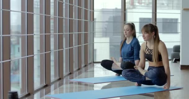 Niñas practican yoga en una habitación grande y luminosa. entrenador y estudiante. concepto de entrenamiento deportivo . — Vídeo de stock