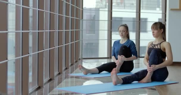 Le ragazze praticano yoga in una grande stanza luminosa. allenatore e studente. concetto di allenamento sportivo . — Video Stock