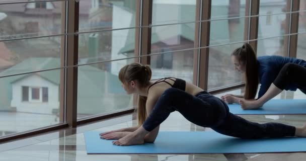A lányok jógáznak egy nagy, világos szobában. Edző és diák. sportképzési koncepció. — Stock videók