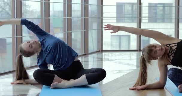 Девушки практикуют йогу в большой, светлой комнате. тренер и студент. концепция спортивных тренировок . — стоковое видео