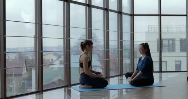 Niñas practican yoga en una habitación grande y luminosa. entrenador y estudiante. concepto de entrenamiento deportivo . — Vídeo de stock