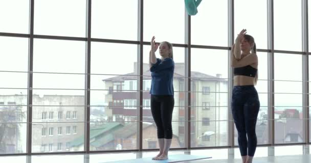 Kızlar büyük, aydınlık bir odada yoga çalışırlar. Koç ve öğrenci. spor eğitimi konsepti. — Stok video