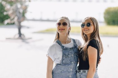 Parkta ya da sokakta yürüyen iki güzel kız. Güneşli bir yaz günü, neşe ve dostluklar.