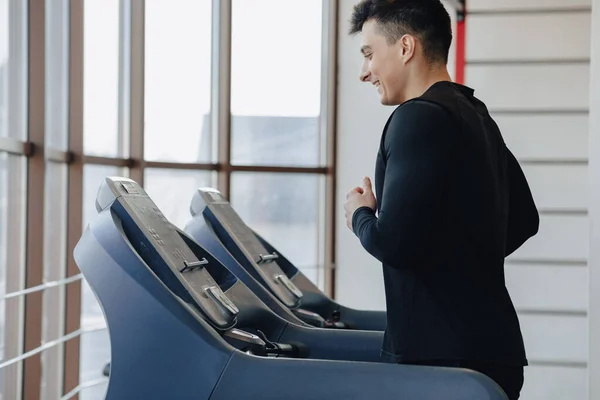Spor salonundaki şık adam koşu bandında antrenman yapıyor. Sağlıklı yaşam tarzı. İyilik.