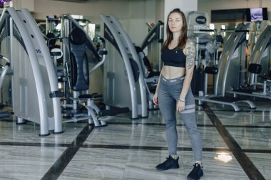 Çekici atletik kız spor salonundaki simülatörlerin arka planında duruyor. sağlıklı yaşam tarzı ve sağlık.