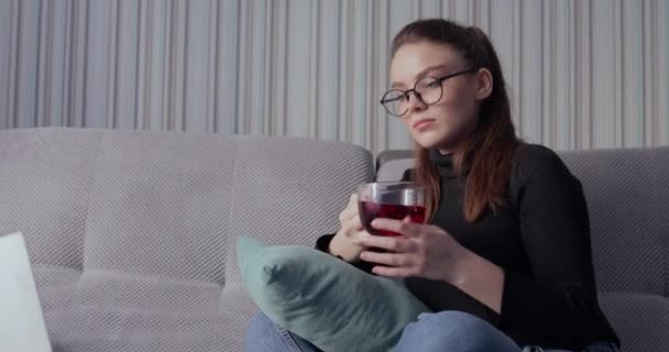 Dziewczyna pracująca na laptopie w domu na kanapie i pijąca herbatę. Zostań w domu i pracuj zdalnie. izolacja w domu. — Wideo stockowe