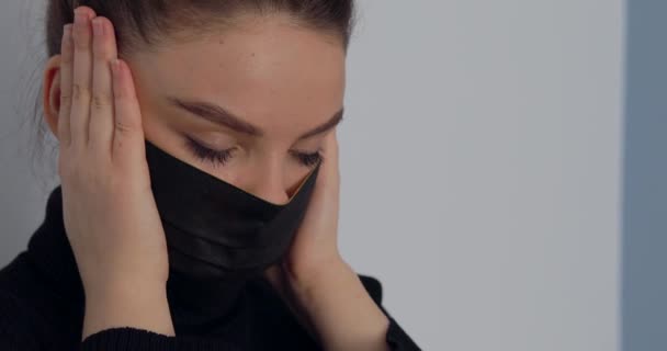 Chica de cerca en una máscara protectora sobre un fondo claro simple. quita y se pone la máscara. protección contra virus y aire sucio . — Vídeos de Stock