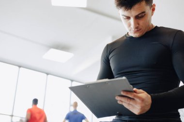 Genç antrenör spor salonunda notlar alıyor. Spor için özel antrenör. spor ve spor.