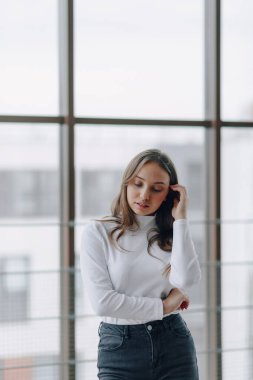 Pencerenin arkasındaki çekici genç kız farklı duygular ve ruh hali gösteriyor. Kapalı alanda hafif arka planda bir kız.